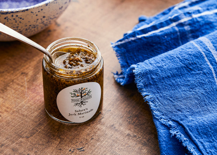 An open jar of Jerk Marinade with a spoon inside of it, next to a bright blue towel